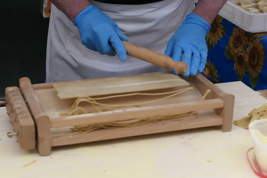 弦を張った木枠の上に生地を置き、麺棒を転がして四角く切る「キタッラ」の道具